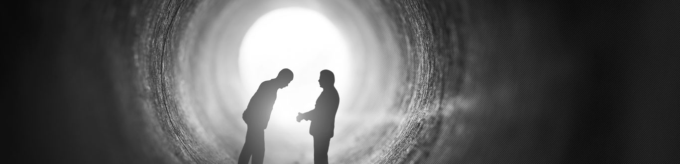 Two men speaking privately in a tunnel